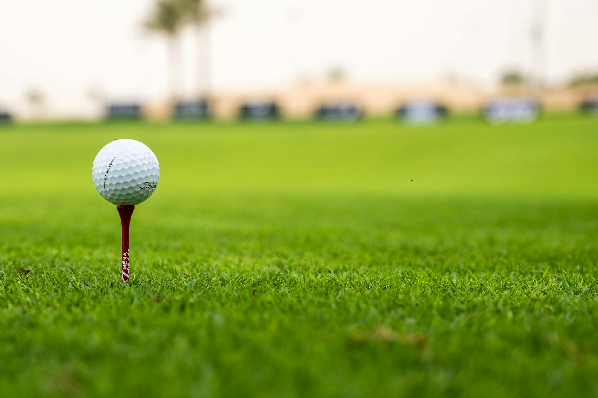 A close-up view of a golf ball on a tee set on a lush green golf course, perfect for sports enthusiasts.